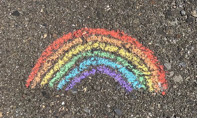 A rainbow drawn with chalk on a pavement 